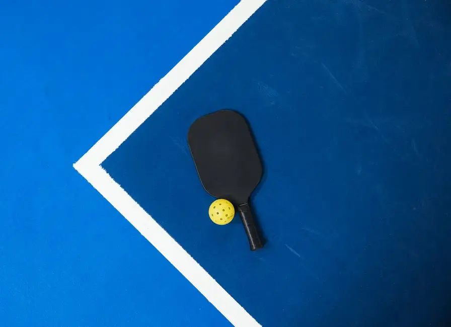 Close-up vợt pickleball và bóng trên sân - chi tiết kỹ thuật dink